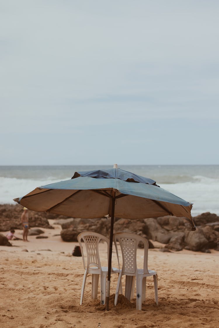 Plastic Chairs Standing On Beach Under Umbrella