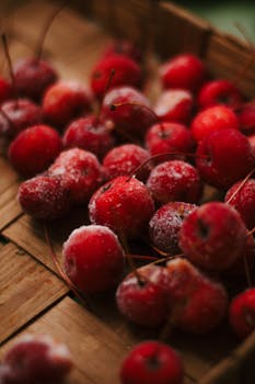 A close-up of frozen red cherries on a rustic wooden surface, perfect for food enthusiasts.