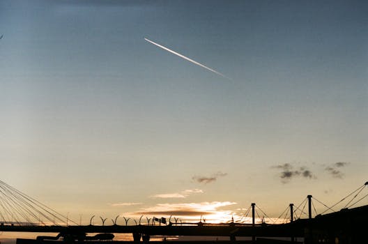 Silhouette of a cable-stayed bridge during a vibrant sunset with a clear sky.