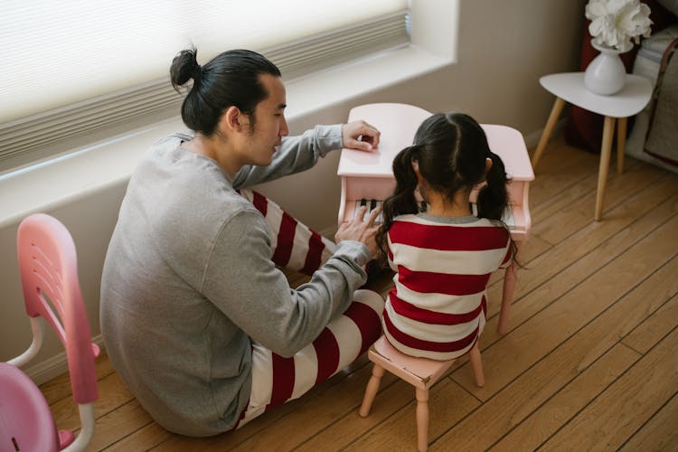 Father Teaching His Child How To Play Piano