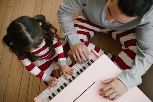 Girl Playing on Piano With Father