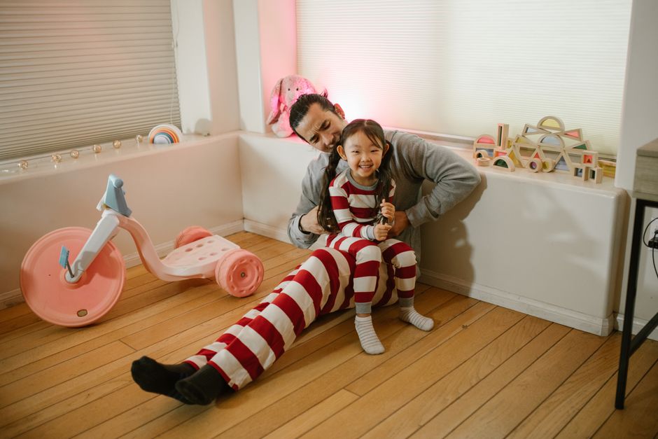 Father and daughter laughing and playing together in a cozy home setting.
