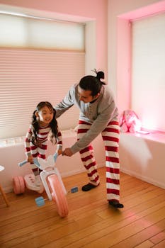 Father and daughter enjoy playful moments together riding indoors in matching pajamas.