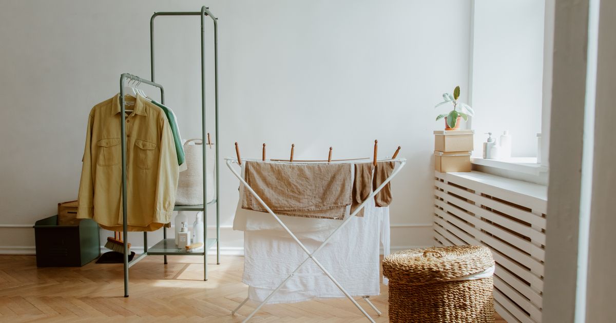 Laundry drying on a rack in a bright white room with a wooden floor
