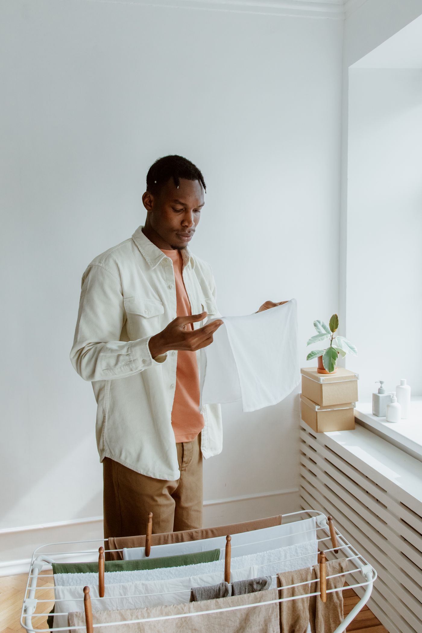 Man hanging freshly washed laundry on a drying rack