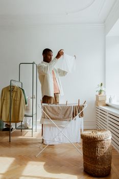 Adult man folds laundry in a bright, airy room. Natural light creates a warm, inviting space.