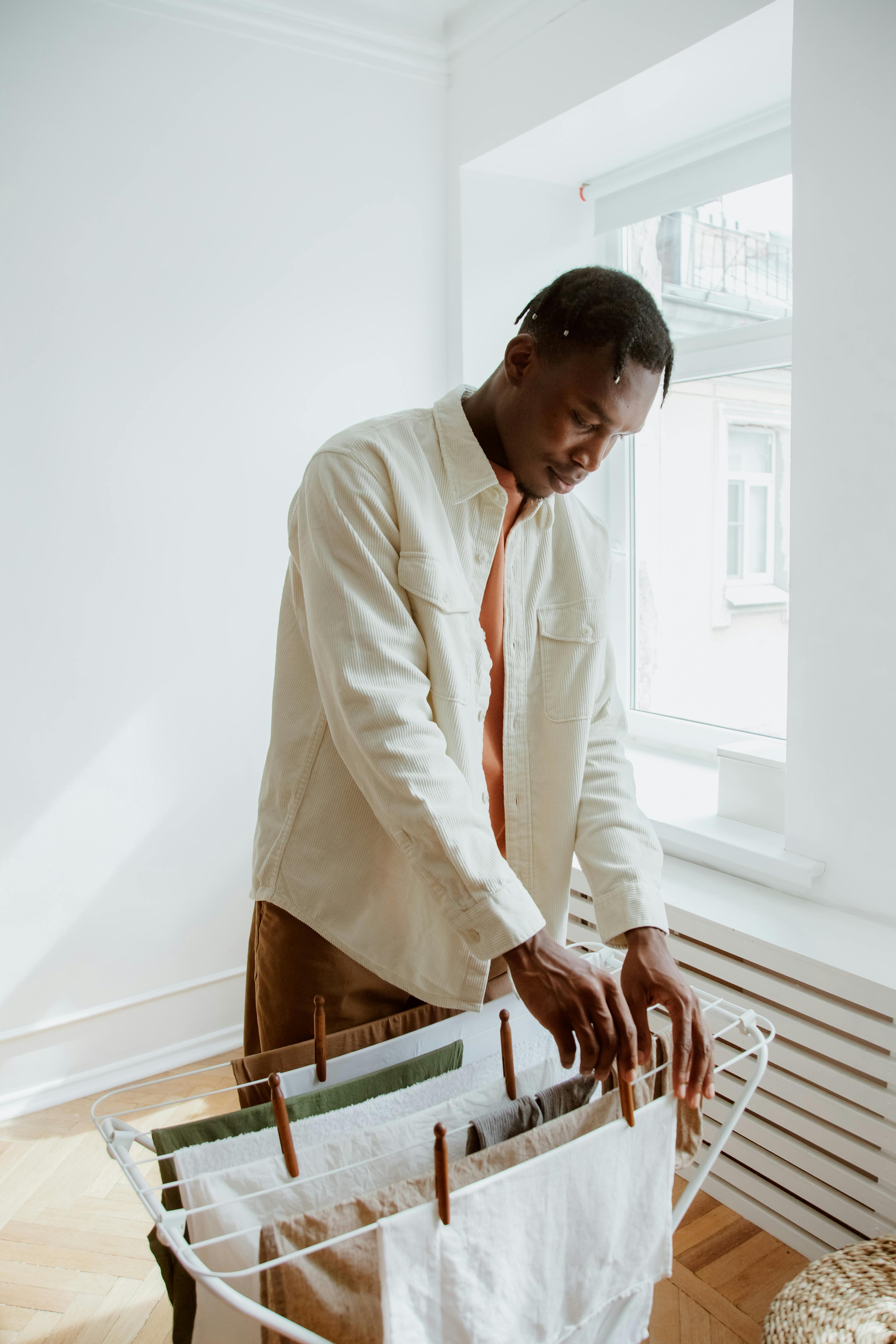 man hanging fresh laundry on dryer