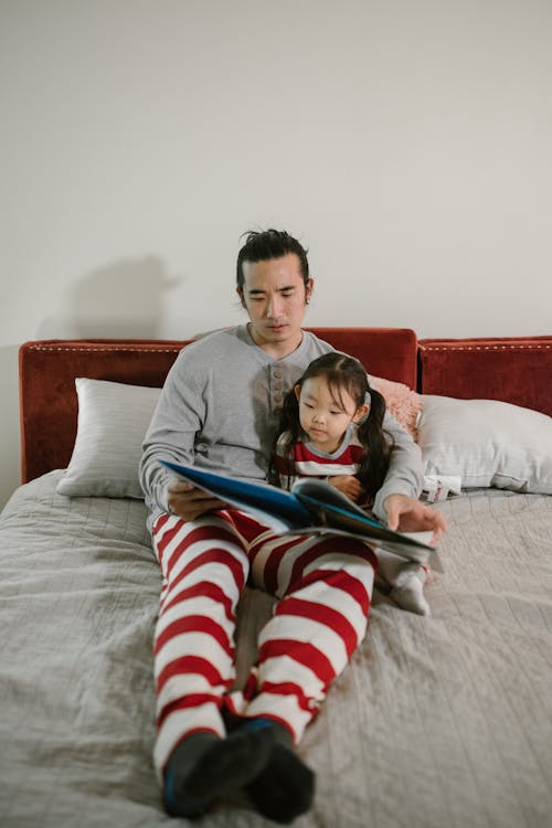 Free Father Reading Book in Bed to His Child Stock Photo