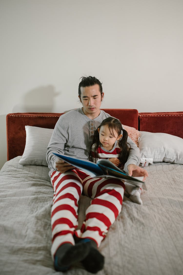 Father Reading Book In Bed To His Child