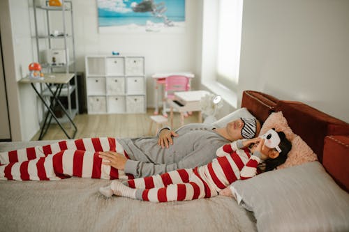 Free Father and Daughter Wearing Pajamas and Sleep Masks in Bed Stock Photo