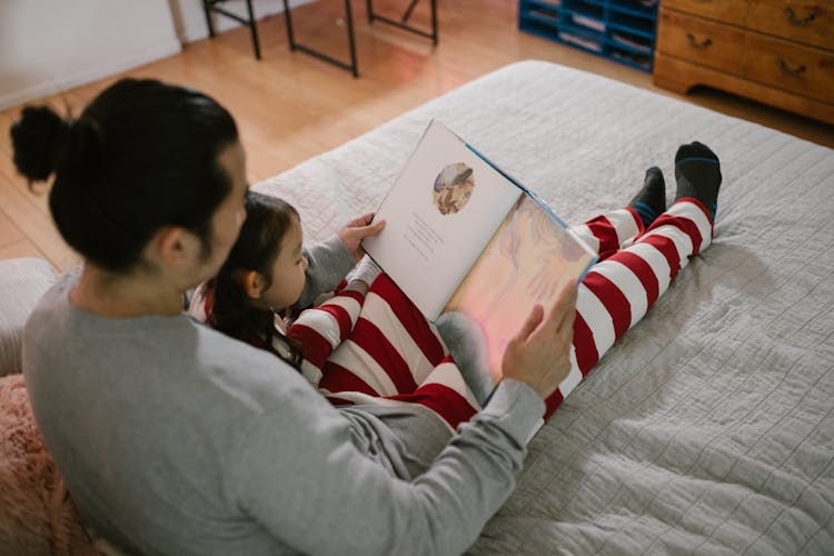 Parent Reading Book To Child In Bed