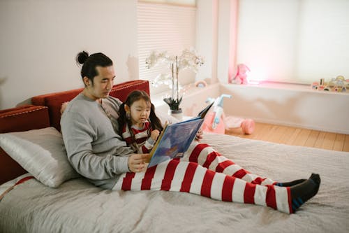 Free Father and Daughter Reading in Bed Stock Photo