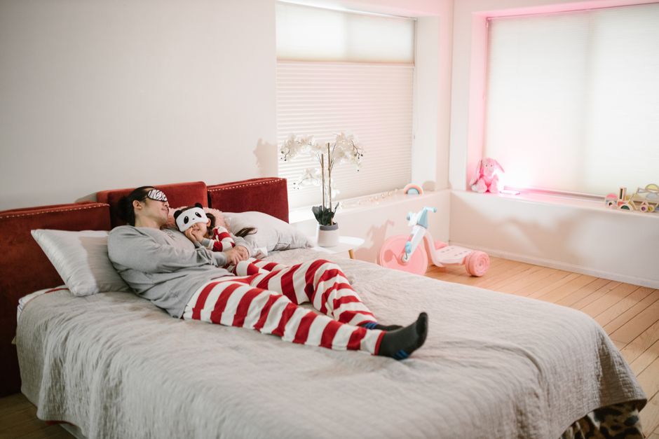 Fotomural Un padre y su hija en pijamas a juego yacen pacíficamente en un dormitorio brillante y acogedor.