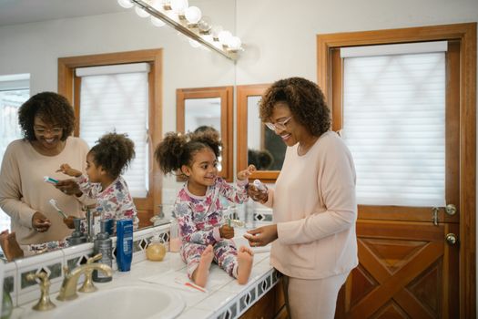 A mother and daughter sharing a joyful morning routine in a bright bathroom.