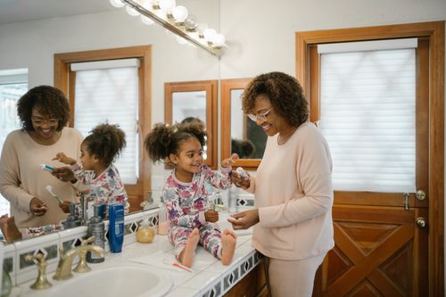 Free A mother and daughter sharing a joyful morning routine in a bright bathroom. Stock Photo