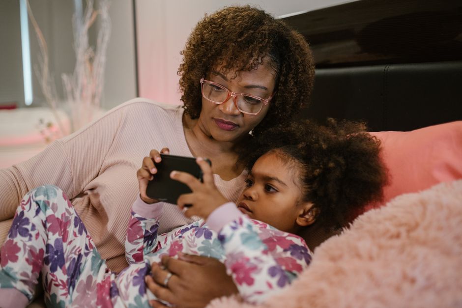 Photo by RDNE Stock project on Pexels A mother and daughter enjoy bedtime together, relaxing with a smartphone in a cozy bedroom setting. - Photo by RDNE Stock project on Pexels