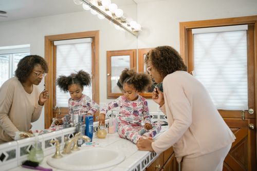 Free A mother and daughter engaging in a morning skincare routine together in the bathroom. Stock Photo