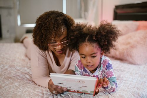 Free A mother and daughter bonding over a bedtime story in a cozy bedroom setting. Stock Photo