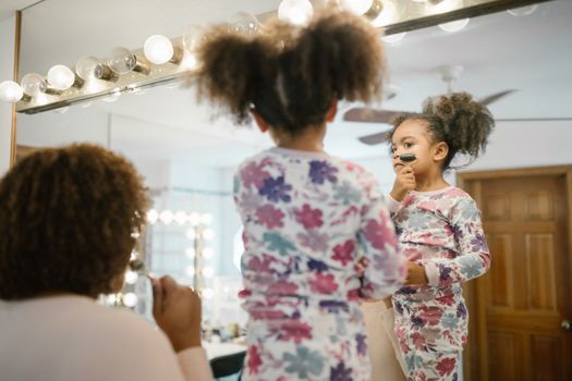 Mother and daughter enjoying a morning beauty routine with jade roller in cozy pajamas.