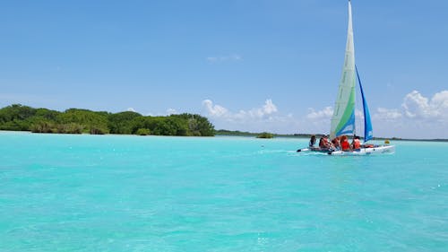 Group of People Riding Sailboat on Body of Water
