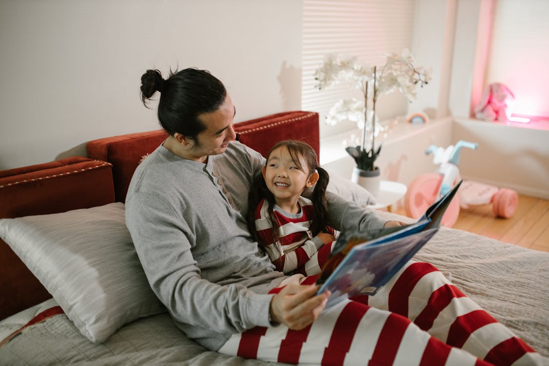 Father and Daughter Smiling while Reading Book