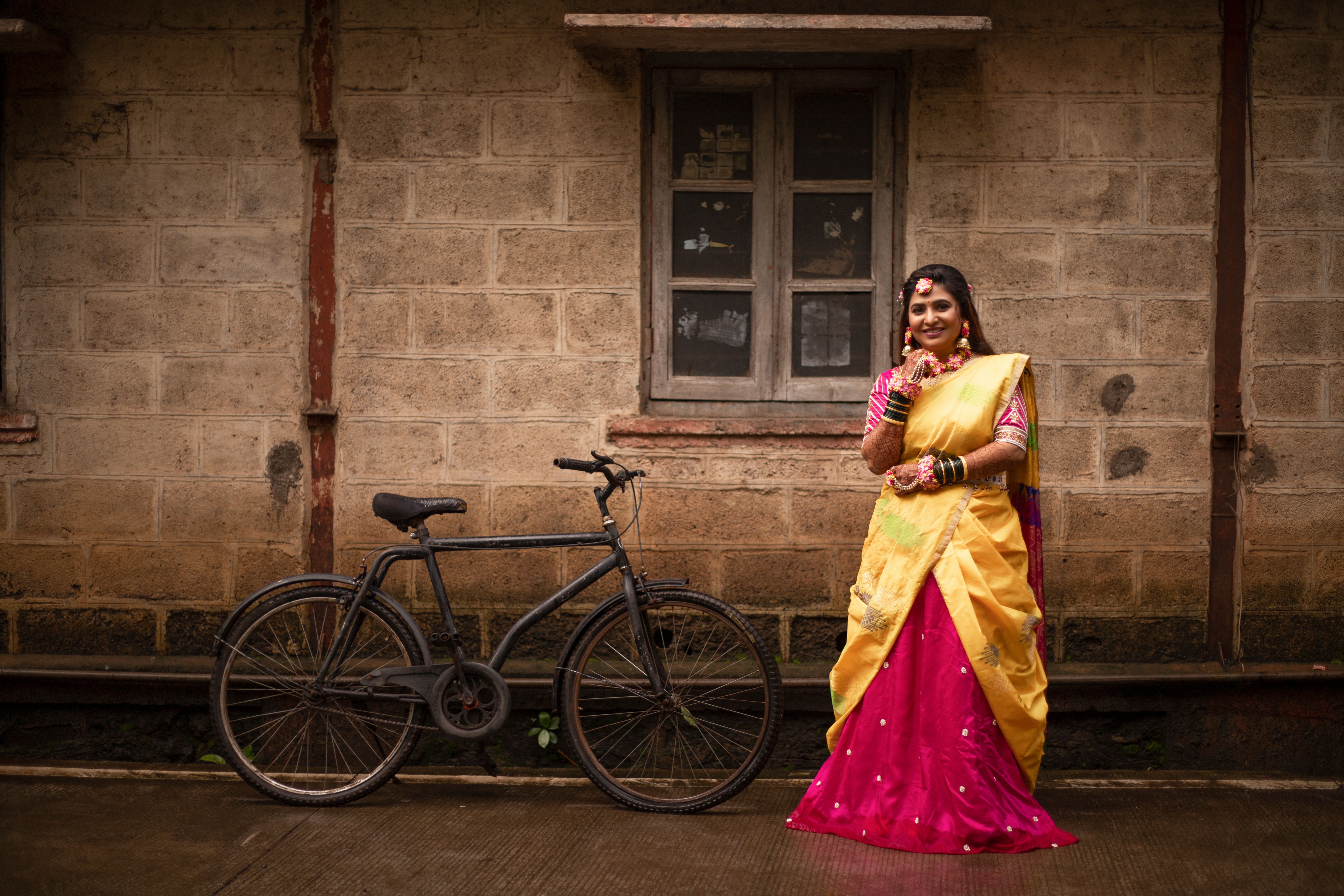 Woman in Traditional Dress Standing Beside a Bicycle · Free Stock Photo