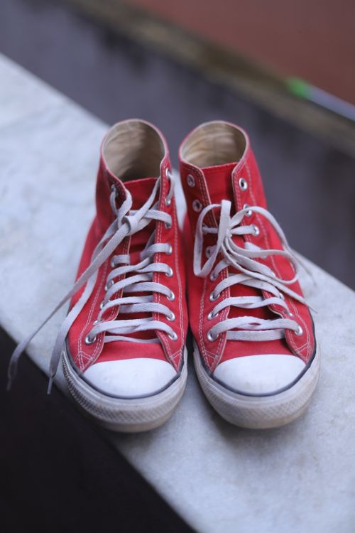 Free A pair of classic red sneakers with white laces on a marble surface, showcasing casual style. Stock Photo