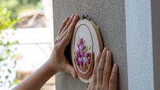 A Person Putting the Embroidered Fabric on the Wall