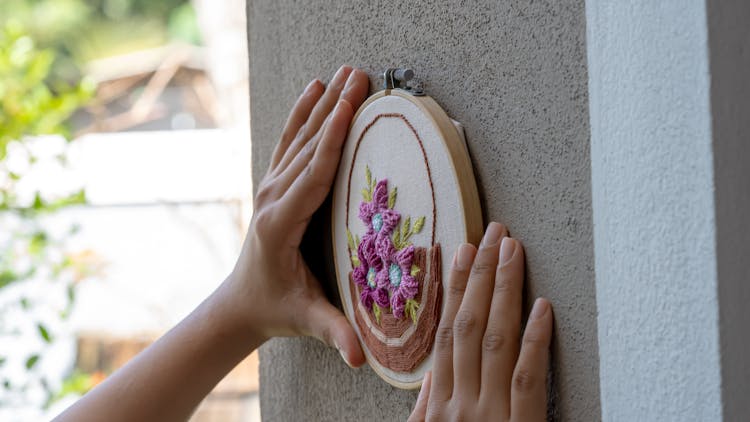 A Person Putting The Embroidered Fabric On The Wall