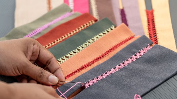 Detailed close-up of hands embroidering various colorful fabrics, showcasing intricate craftwork.