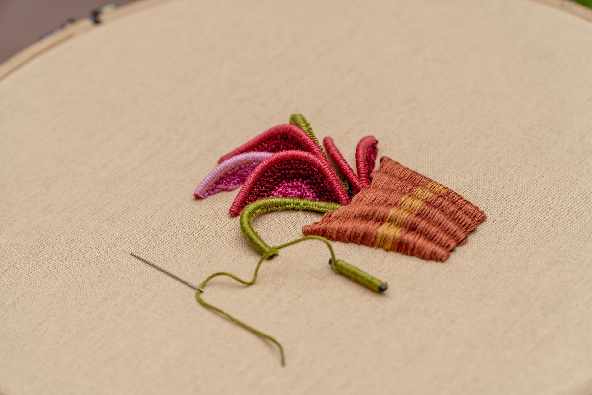 Detailed close-up of an embroidery design with needle and yarn on fabric.