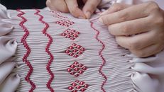 Intricate hand stitching on fabric with decorative beads, showcasing artistry and craftsmanship.