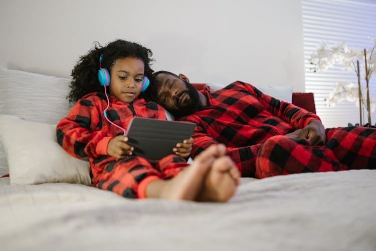 Child Using Tablet By Sleeping Father