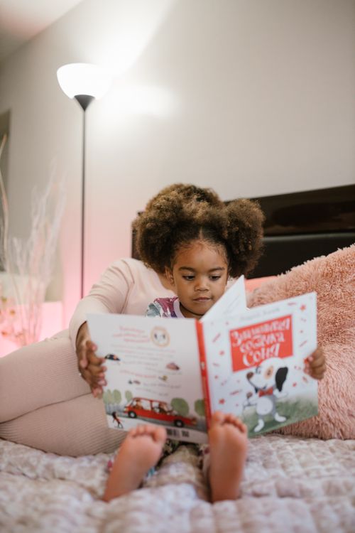 Free A mother and daughter enjoy quality time reading a book on a cozy bed. Stock Photo