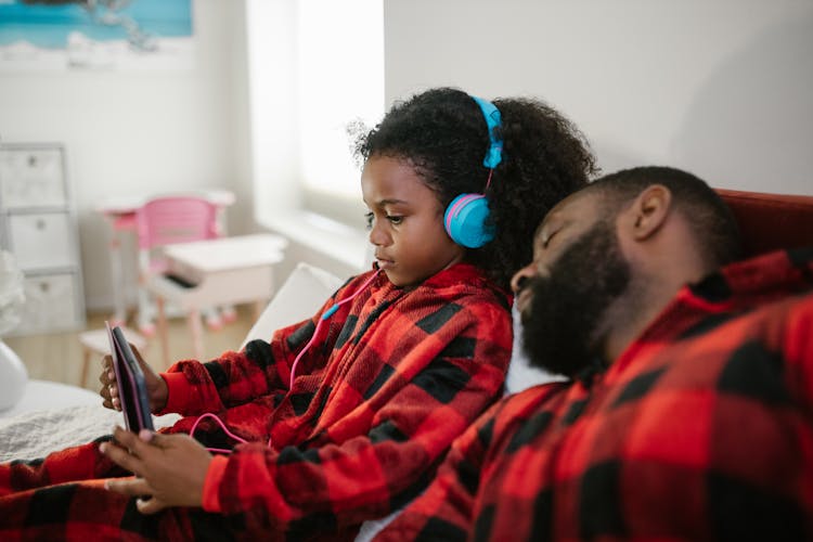 Daughter Listening To Music With Sleeping Father