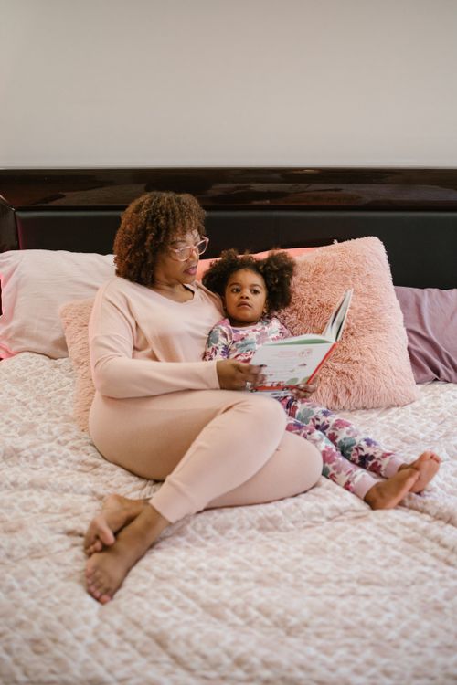 Free A mother and daughter enjoying a cozy reading time in bed, sharing a storybook. Stock Photo