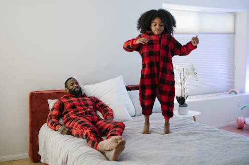 Free Girl Jumping on Bed with Father Supervision  Stock Photo