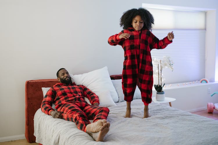 Girl Jumping On Bed With Father Supervision 