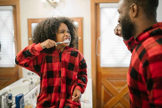A father and daughter in matching pajamas brushing their teeth in a cozy bathroom.