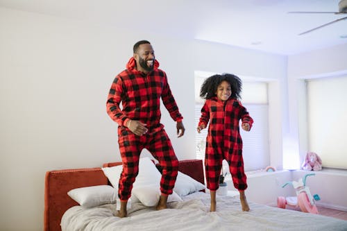 Free Father and Child Jumping on Bed Stock Photo