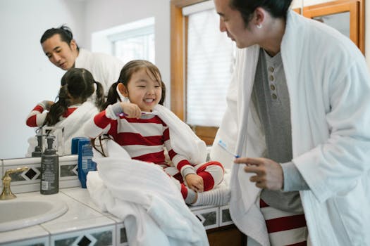 A father and daughter enjoy brushing teeth together in a cozy bathroom setting.