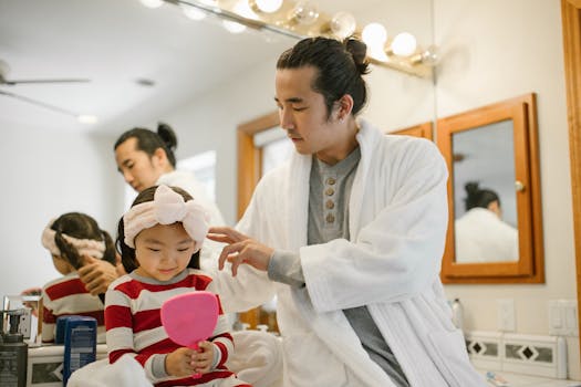 Father helping daughter with her hair in a relaxing morning bathroom routine.