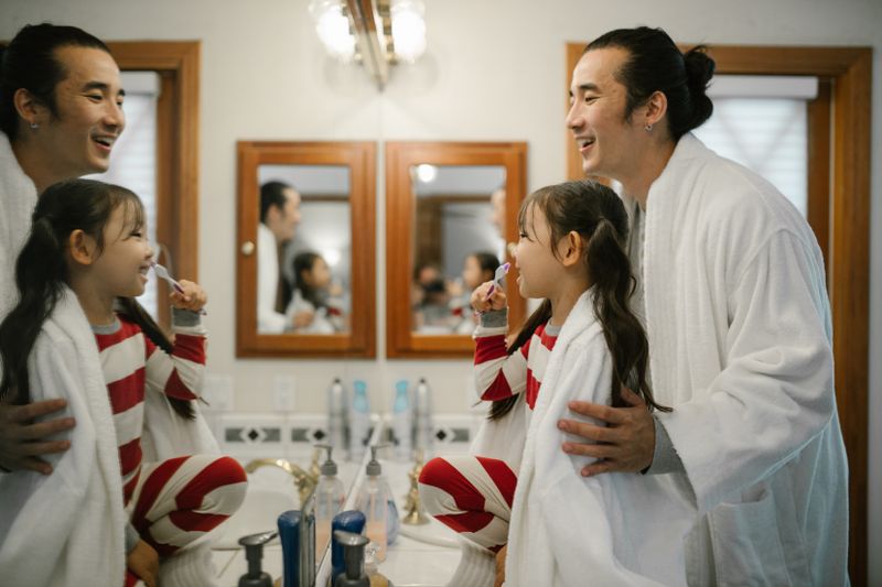 Brosse à dents enfant personnalisée et hygiène dentaire Père aidant sa fille à se brosser les dents dans la salle de bain, hygiène bucco-dentaire enfant