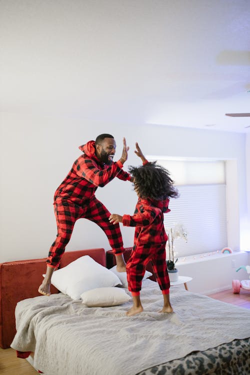 Free Father and Daughter Jumping on Bed Stock Photo