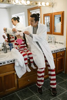 Father and daughter bonding during morning routine in bathroom, wearing matching pajamas.