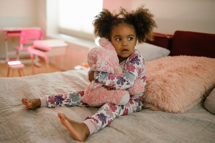 Child Hugging Toy On Bed