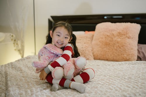 Smiling Child Embracing Toy in Bed