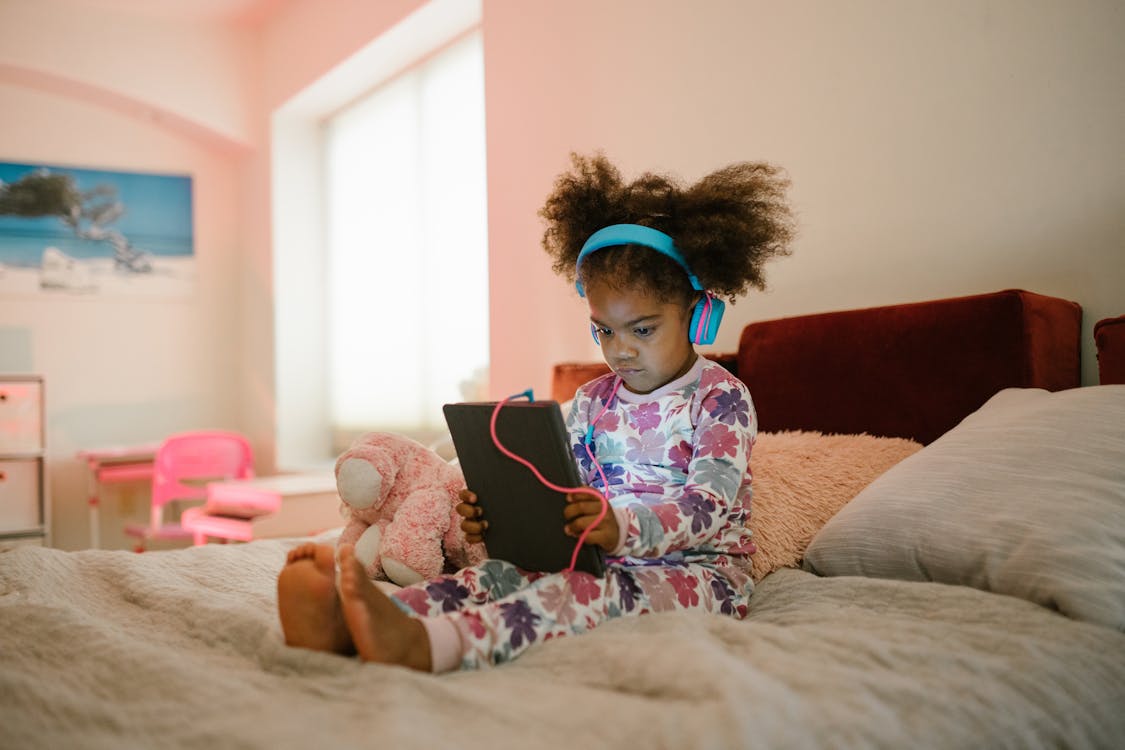 Child Sitting on Bed with Tablet