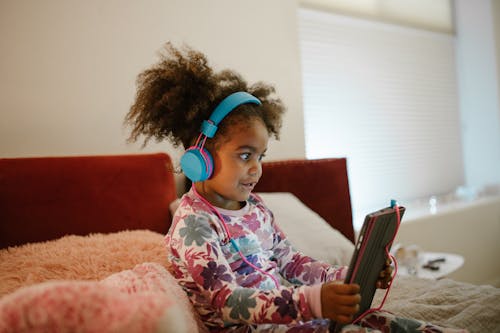 Free Child Using Tablet in Bed Stock Photo