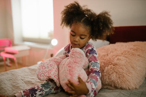 Free Child Holding Toy in Bed Stock Photo